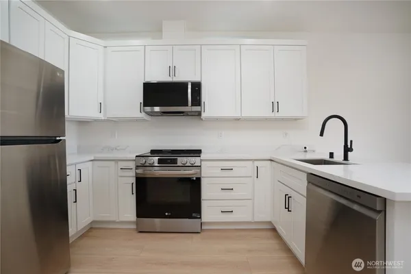 a kitchen with stainless steel appliances granite countertop a refrigerator stove and white cabinets