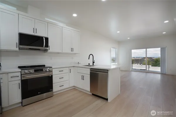 a kitchen with stainless steel appliances granite countertop a stove a sink and a microwave