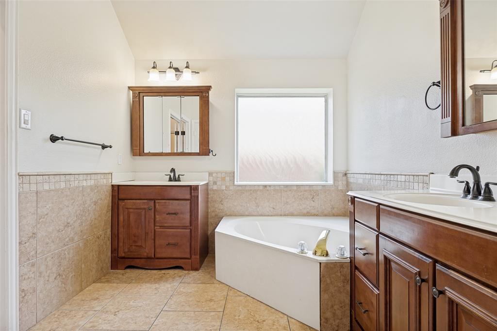 2100 Los Rios Boulevard Plano, TX 75074 - Photo 15 of 25 Bathroom featuring a corner soaking tub, two wood-finish vanities with countertop sinks, and tiled flooring
