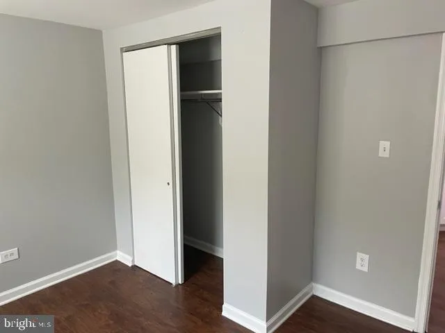 a view of an empty room with closet and wooden floor