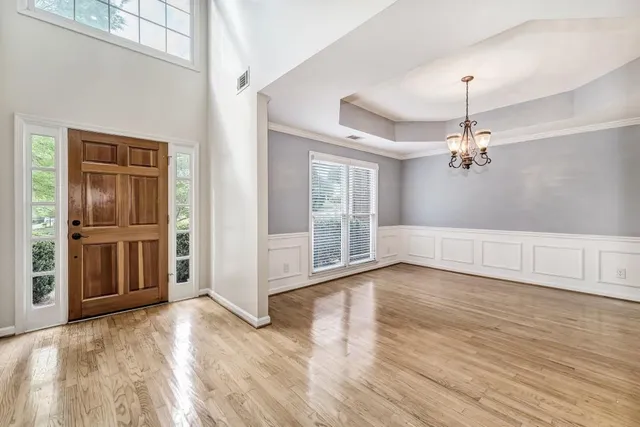 a view of a livingroom with wooden floor a ceiling fan and windows