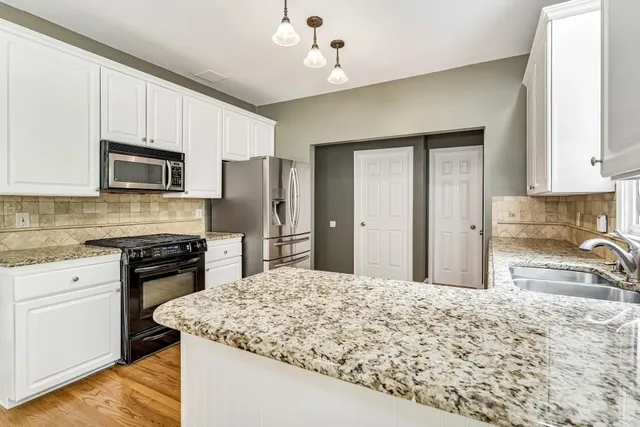 a kitchen with stainless steel appliances granite countertop a stove refrigerator sink and microwave