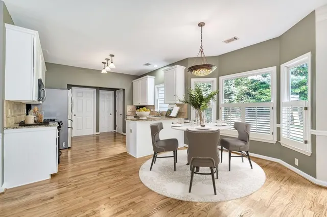 a dining room with wooden floor a chandelier a glass table and chairs