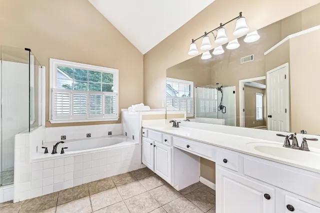 a spacious bathroom with a tub a double vanity sink a window and mirror