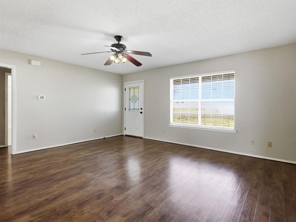 701 College Street Celeste, TX 75423 - Photo 6 of 29 an empty room with wooden floor ceiling fan and windows