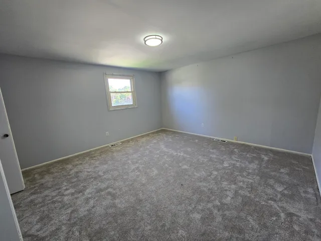 a brick house with a yard plants and big trees