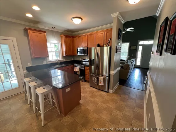 a kitchen with stainless steel appliances granite countertop a refrigerator a stove a sink a dining table and chairs