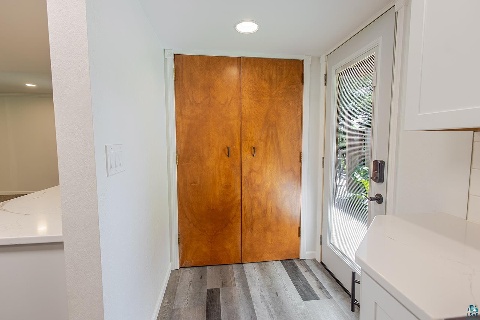 29 Ridge Road Esko, MN 55733 - Photo 14 of 41 Wood-finish flooring and recessed lighting illuminate this space, featuring a full-light panel door, a wood bifold closet, and a white quartz countertop