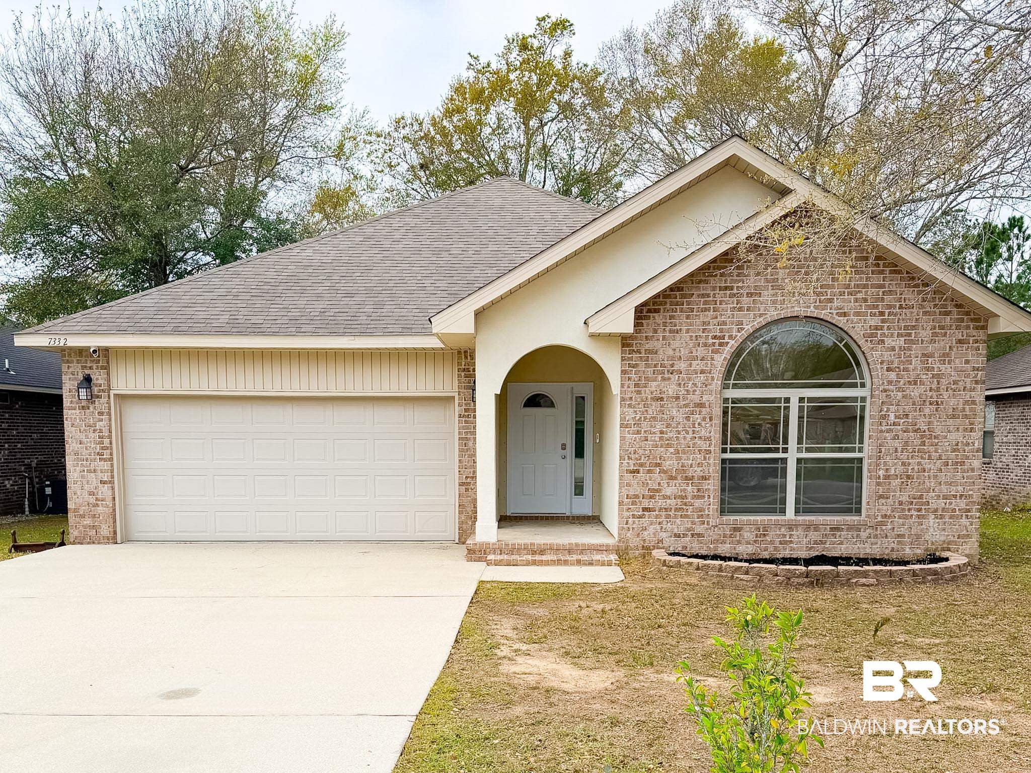 View of front of home with an attached garage, concrete driveway, brick siding, and a shingled roof
