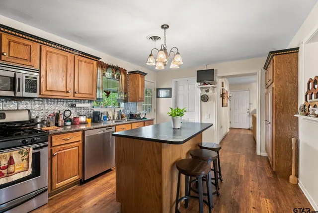 a kitchen with stainless steel appliances granite countertop a stove top oven a refrigerator a sink and dishwasher with wooden floor