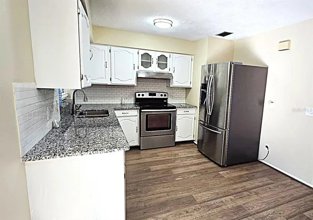 a kitchen with granite countertop a refrigerator and a stove top oven
