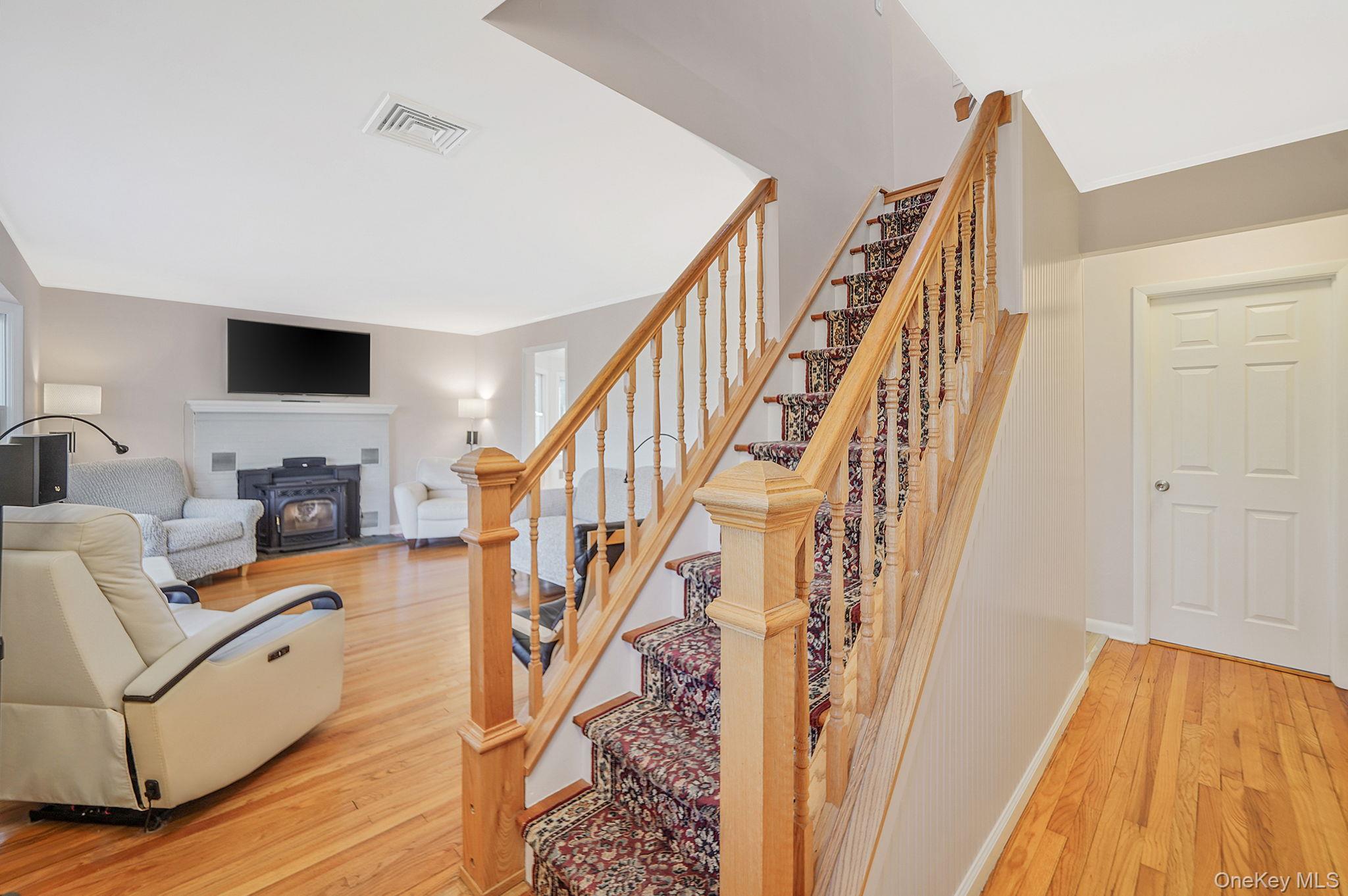 12 Harbor Beach Road Miller Place, NY 11764 - Photo 3 of 45 Staircase featuring wood finished floors and a wood stove