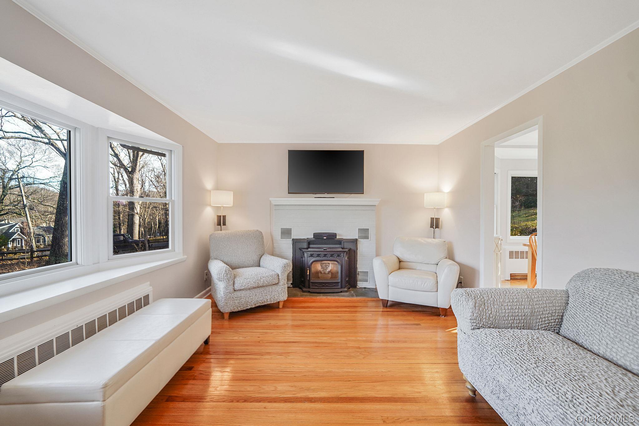 12 Harbor Beach Road Miller Place, NY 11764 - Photo 4 of 45 Living area featuring a wood stove, light wood-style floors, radiator, plenty of natural light, and crown molding