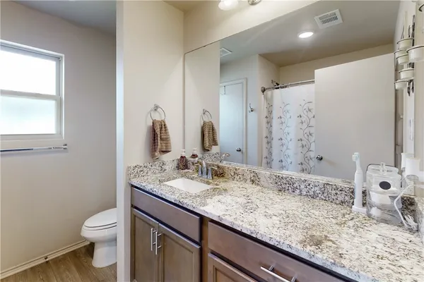 a bathroom with a granite countertop sink a toilet and a mirror