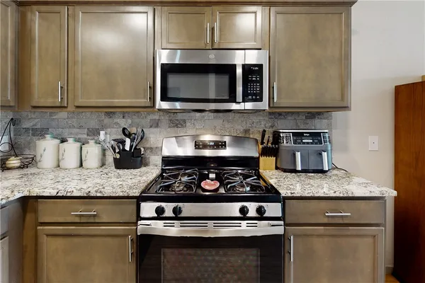 a kitchen with granite countertop stainless steel appliances a stove a microwave and sink