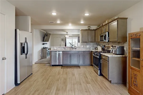a kitchen with stainless steel appliances a sink wooden floor and a refrigerator