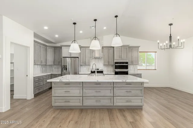 a large kitchen with granite countertop a stove a sink and a wooden floors