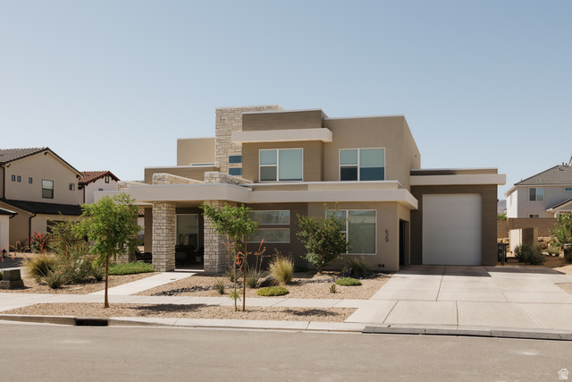 629 Spring Lily Drive St. George, UT 84790 - Photo 1 of 50 Modern stucco exterior with stone accents, a concrete driveway, a front walkway, an integrated garage, and low-maintenance landscaping