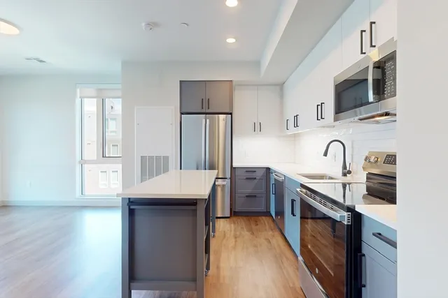 a kitchen with stainless steel appliances granite countertop a sink stove refrigerator and cabinets