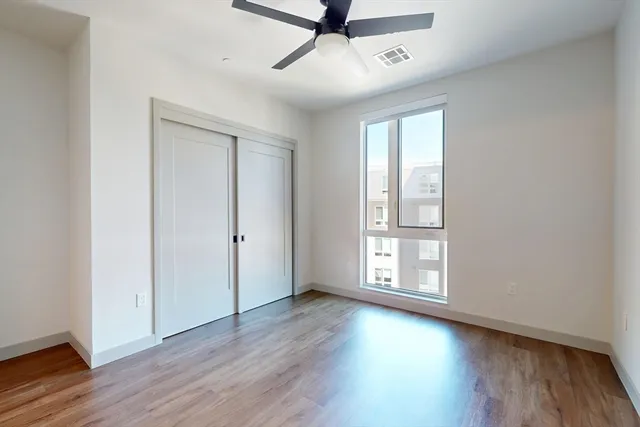 an empty room with wooden floor and windows with curtains