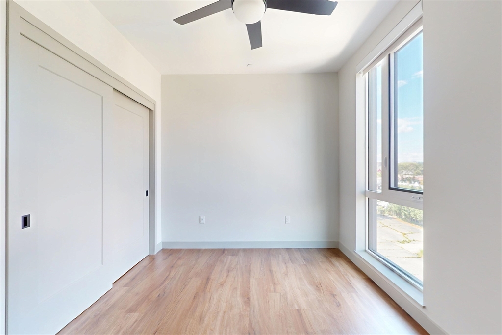 80 Rugg Road, Unit 1311 Boston, MA 02134 - Photo 14 of 20 an empty room with wooden floor and windows