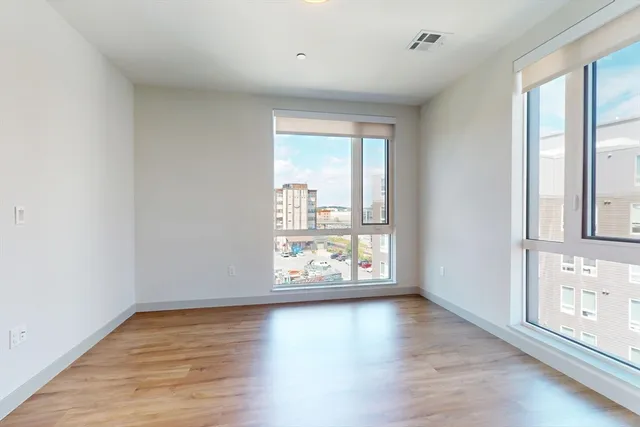 an empty room with wooden floor and windows