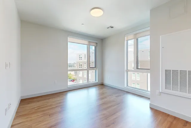 an empty room with wooden floor and windows