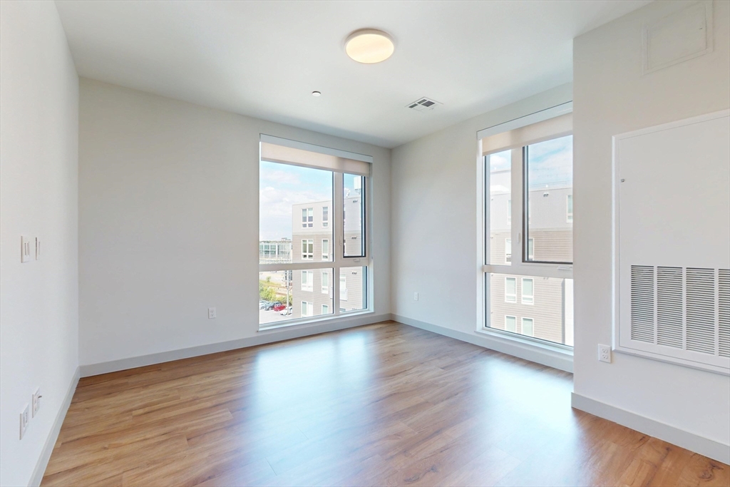 80 Rugg Road, Unit 1311 Boston, MA 02134 - Photo 6 of 20 an empty room with wooden floor and windows