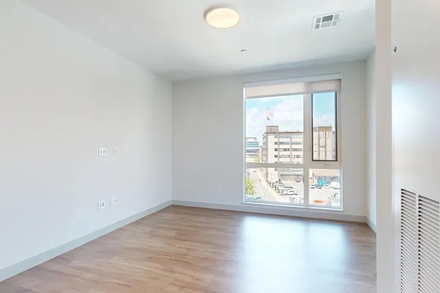 an empty room with wooden floor and windows