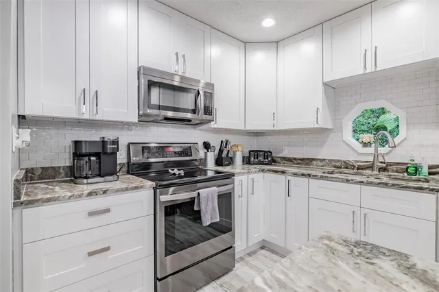a kitchen with granite countertop white cabinets and white appliances