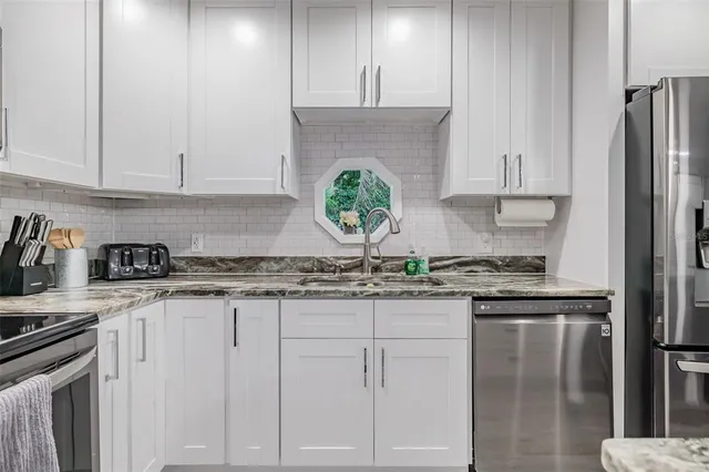 a kitchen with granite countertop a sink stainless steel appliances and cabinets