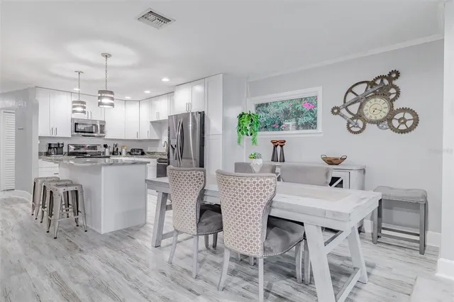 a kitchen with kitchen island a dining table chairs stainless steel appliances and cabinets