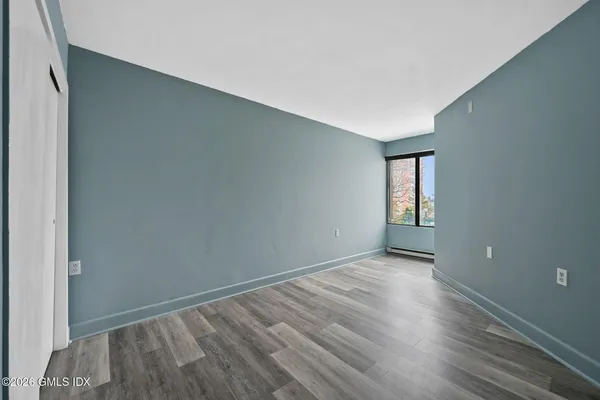 a view of an empty room with wooden floor and a window