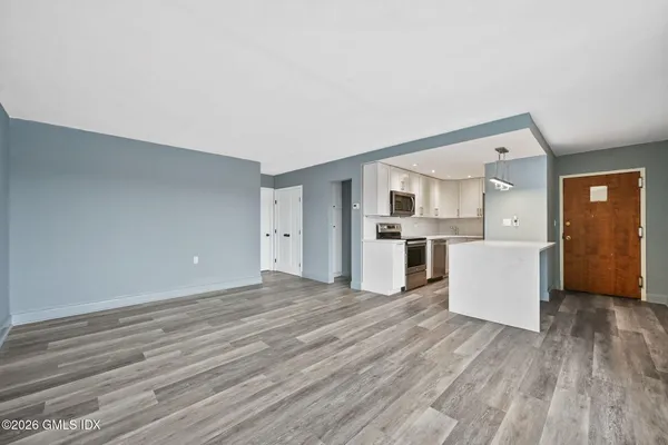 a view of empty room with wooden floor and kitchen