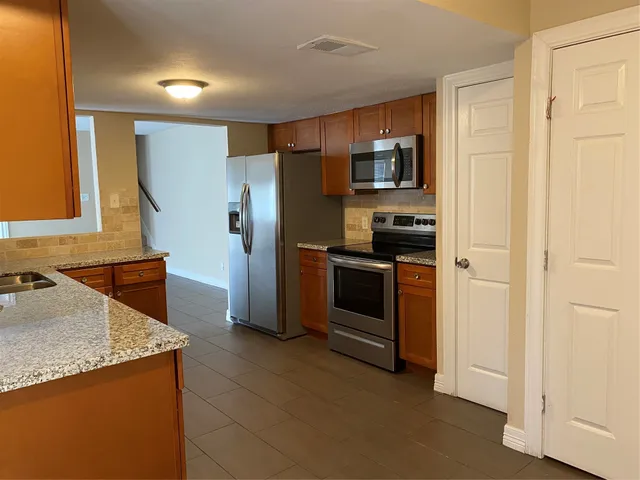 a kitchen with stainless steel appliances granite countertop a refrigerator and a stove
