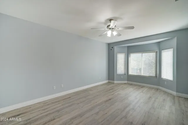 a view of an empty room with chandelier fan and wooden floor