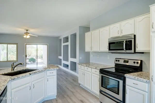 a kitchen with stainless steel appliances granite countertop a sink a stove a microwave and wooden cabinets