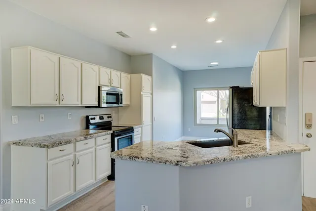 a kitchen with granite countertop a sink and white cabinets