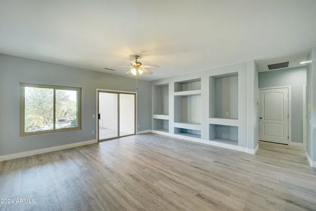 an empty room with wooden floor chandelier and windows