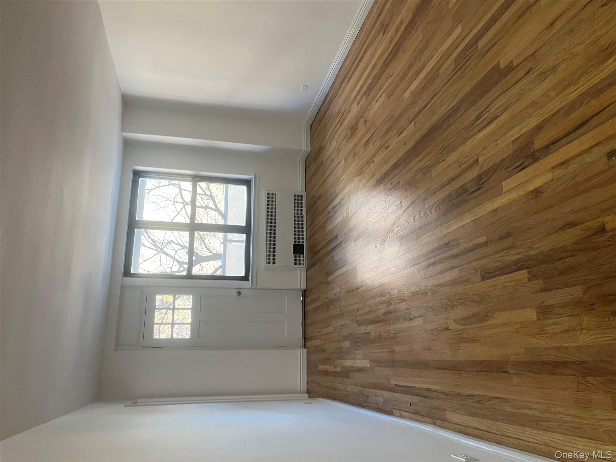 83-40 Austin Street, Unit 3U Queens, NY 11415 - Photo 6 of 8 an empty room with wooden floor and windows