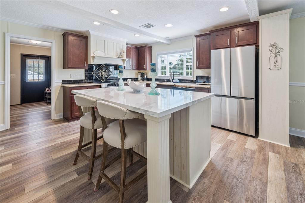 1175 Southwest 248th Avenue Steinhatchee, FL 32359 - Photo 29 of 54 a kitchen with kitchen island a refrigerator a stove a sink and a dining table with wooden floor