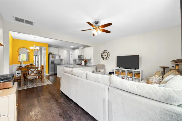 a living room with furniture and a flat screen tv with kitchen view