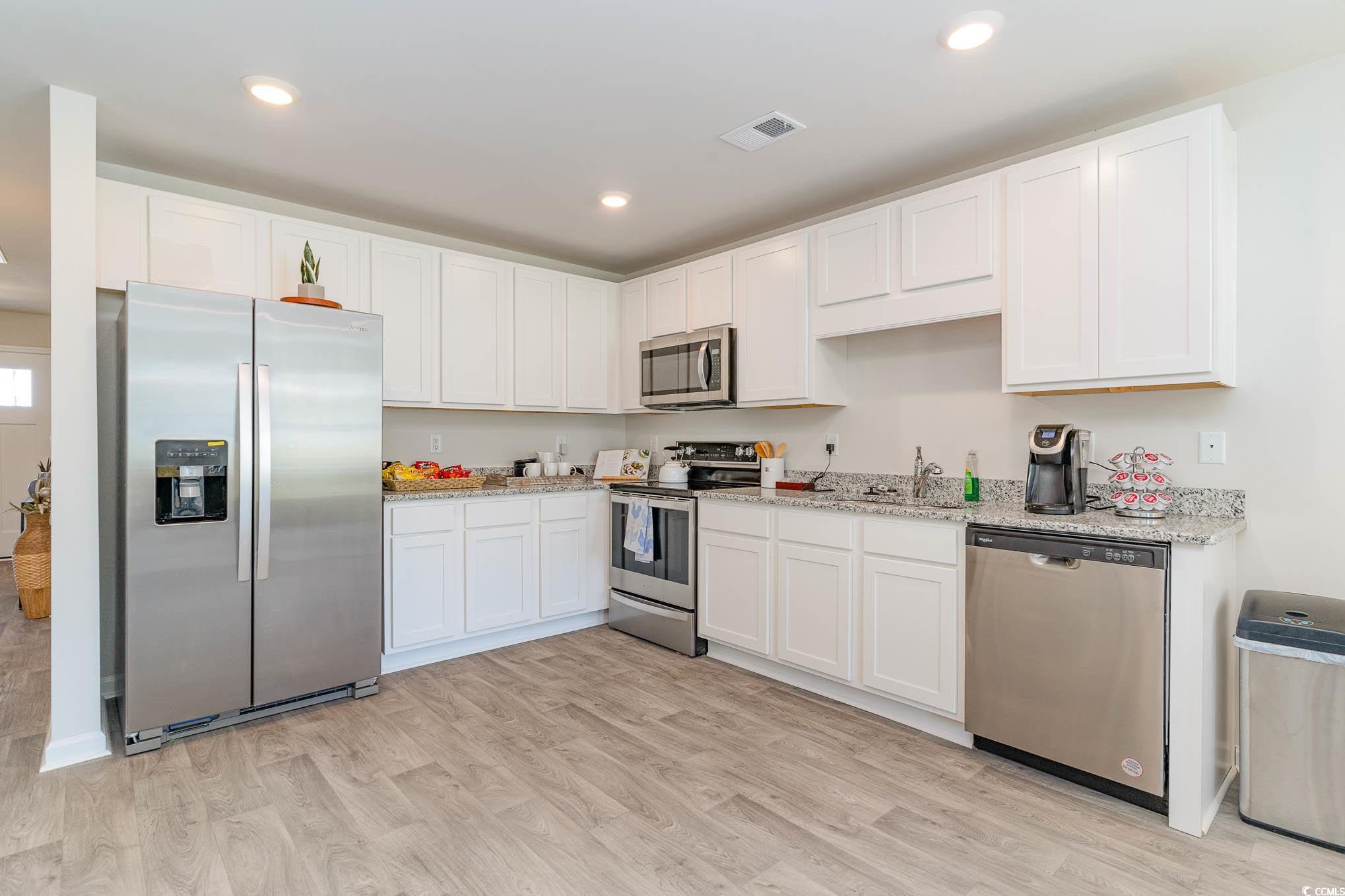 243 Teddy Bear Loop Conway, SC 29526 - Photo 6 of 24 Kitchen featuring appliances with stainless steel finishes, white cabinetry, light stone counters, light wood-type flooring, and recessed lighting