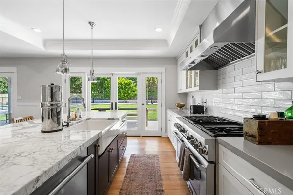a kitchen with stainless steel appliances kitchen island a large stove a sink a counter space wooden floor and cabinets