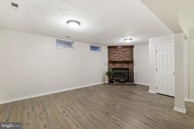 a view of an empty room with wooden floor and a fireplace
