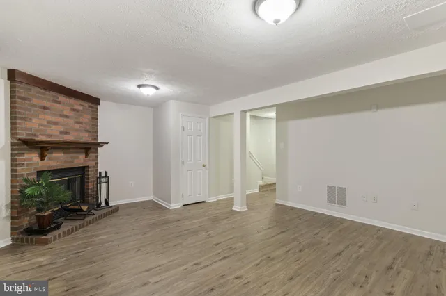 an empty room with wooden floor fireplace and windows