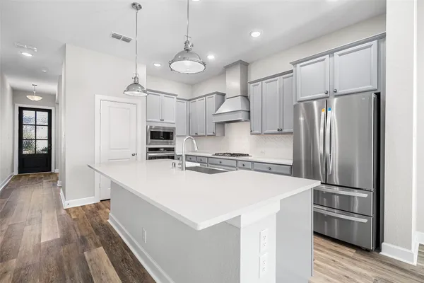 a kitchen with stainless steel appliances a refrigerator sink and wooden floor