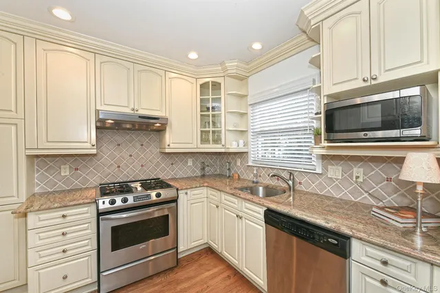a kitchen with granite countertop a sink stainless steel appliances and cabinets