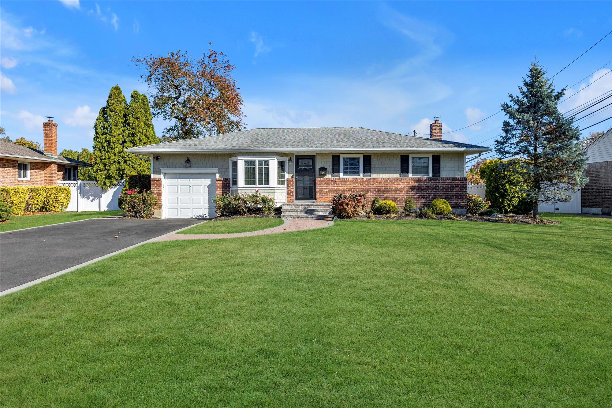 Ranch-style house featuring a garage and a front lawn