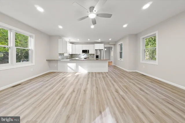 a view of an empty room with a window and wooden floor